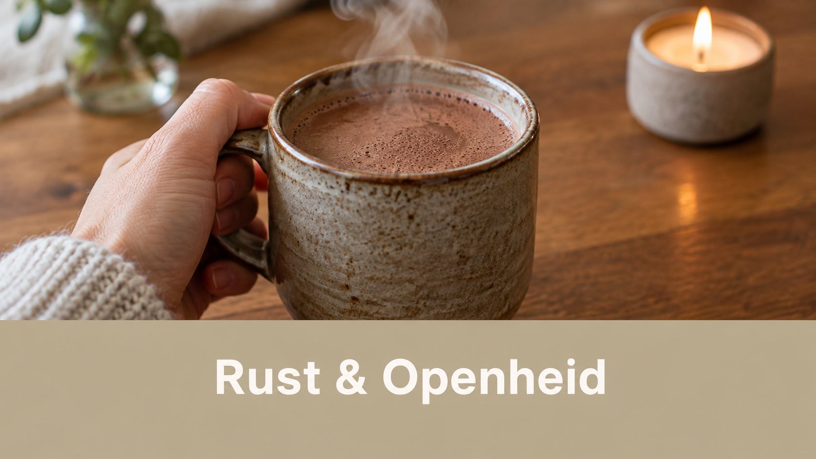 Een hand die een warme mok met dampende cacao vasthoudt bij een brandende kaars op tafel.